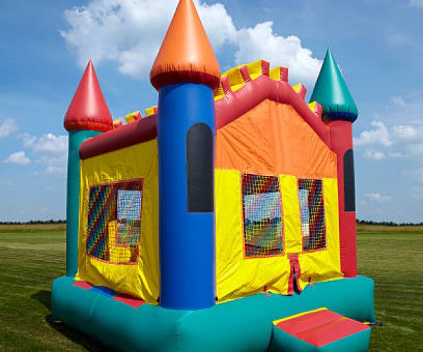 Stock photo of a children's bouncy castle inflatable jumper playground in a grass field with a blue sky.
